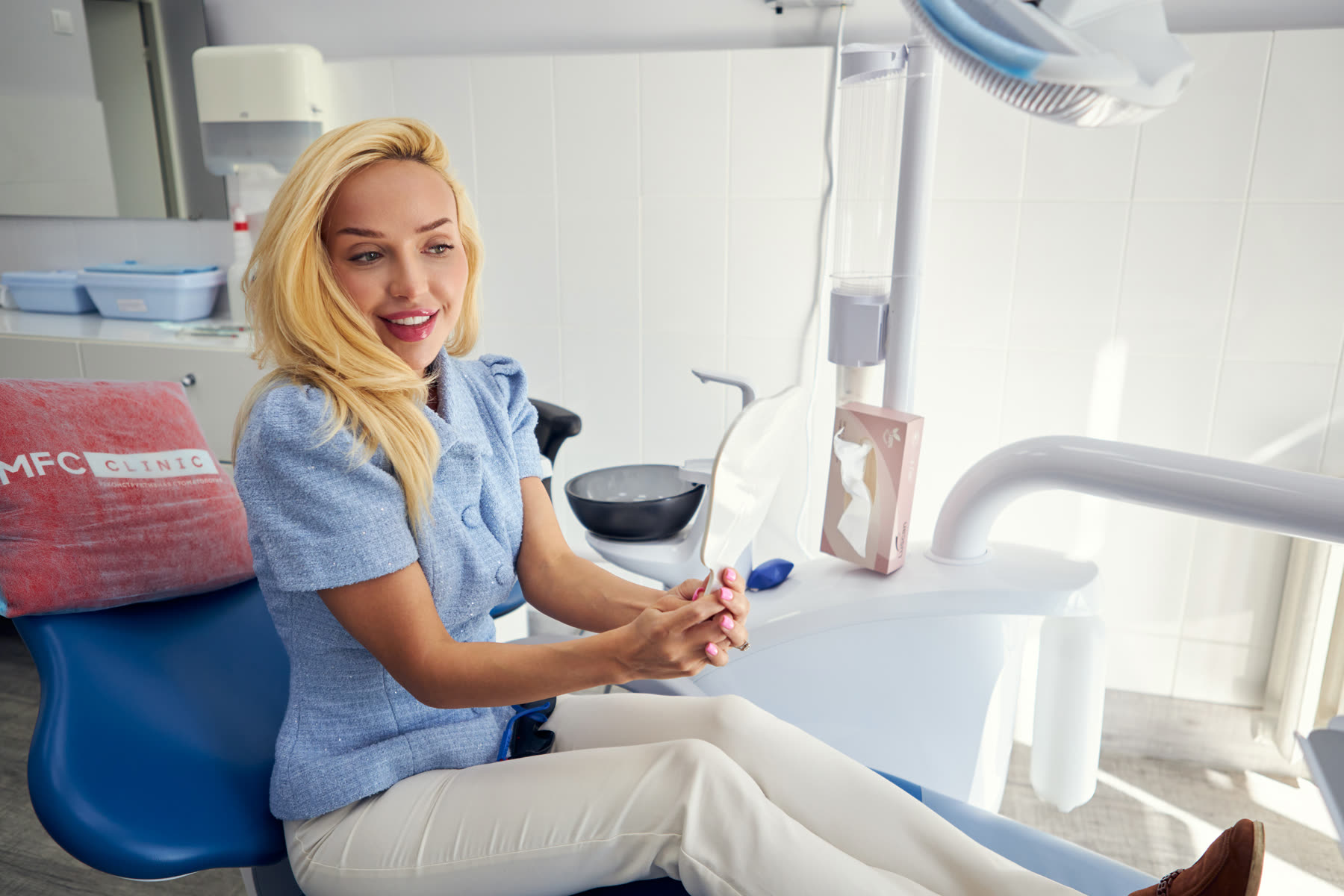 Пациентка улыбается после приёма в клинике MFC Clinic